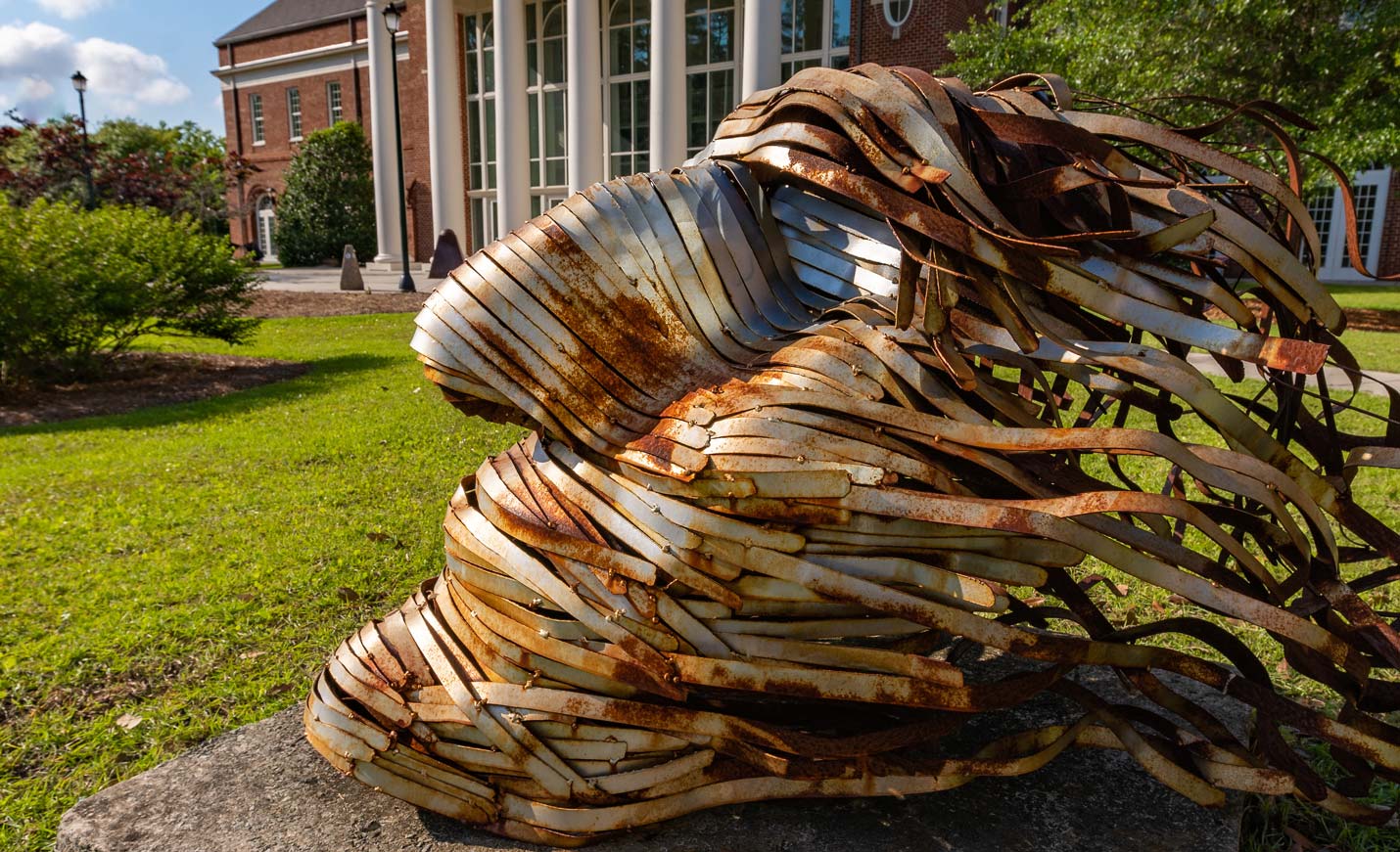 A metal sculpture of a face in front of the Cultural Arts Building