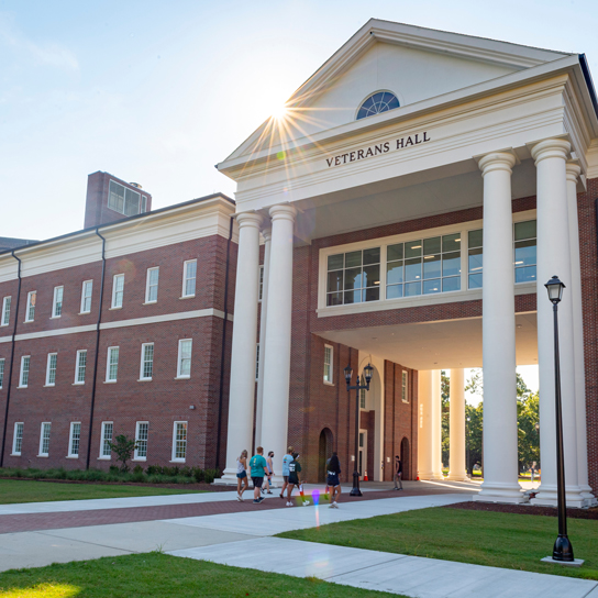 Exterior view of Veterans Hall, a large two-story brick building with massive white Georgian columns at the vaulted entrance.