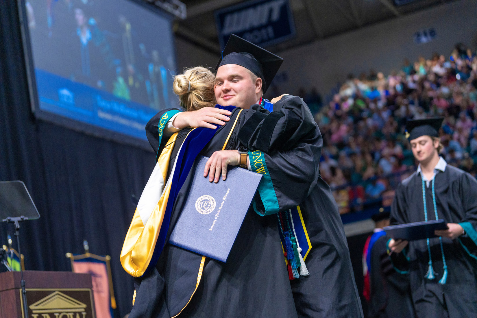 students hug at commencement