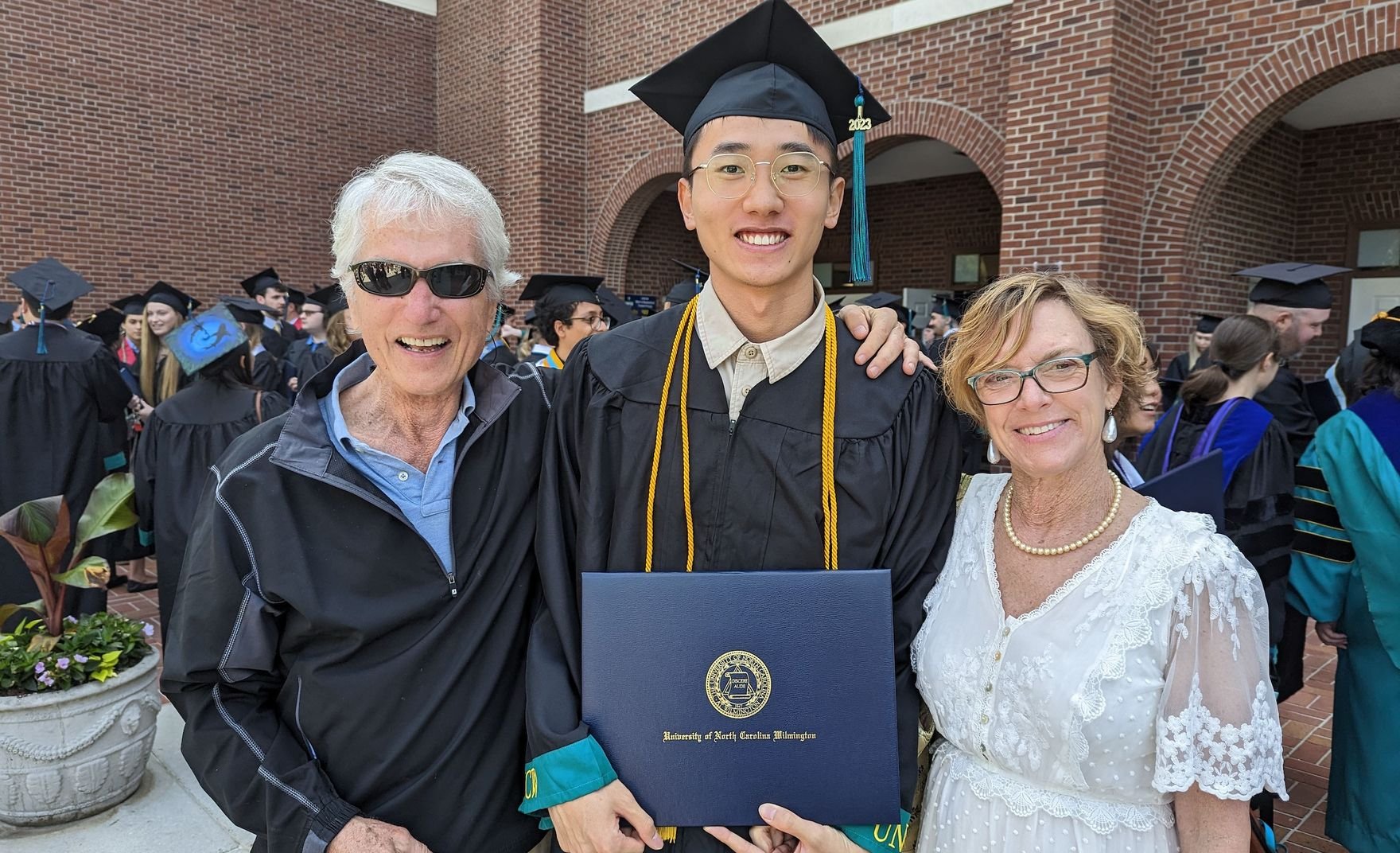 student showing diploma with two elderly people