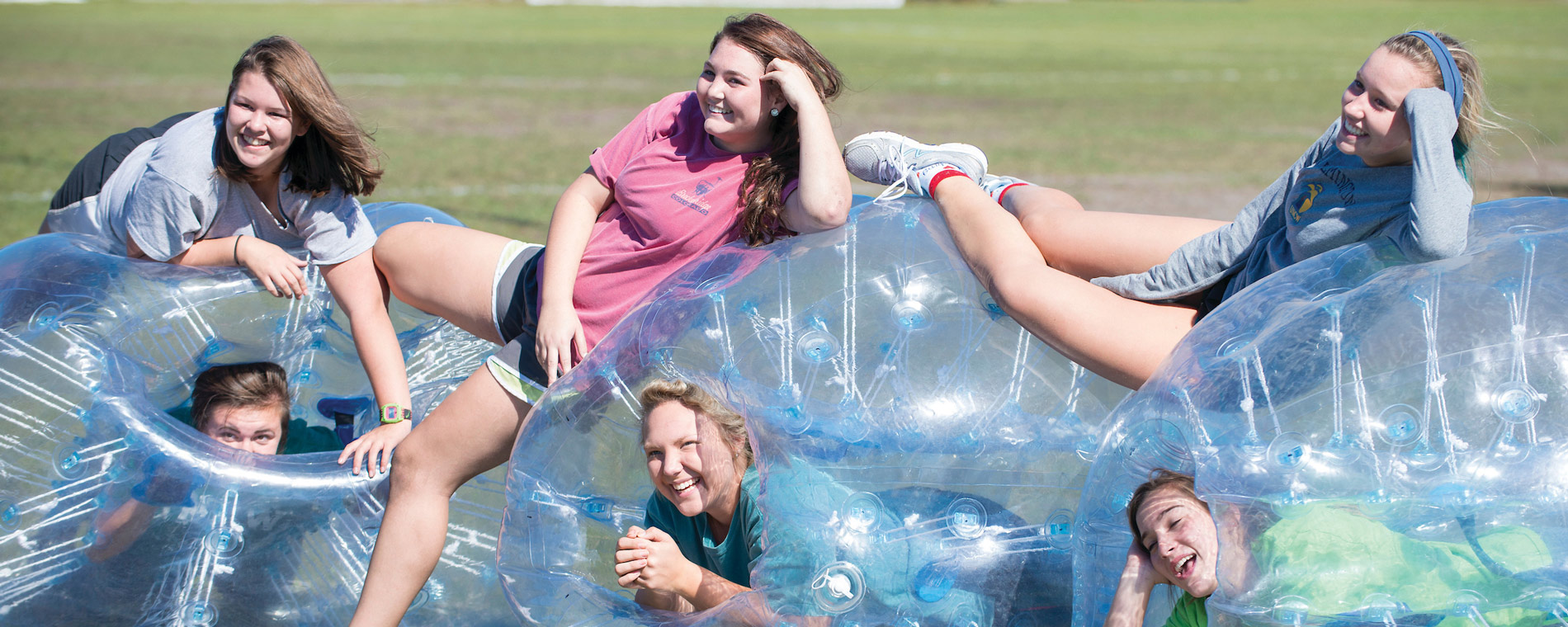 Students sitting inflatable bubbles on a field