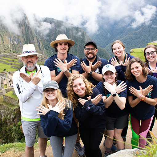 Students standing on a mountain with a professor holding up seahawk signs with their hands