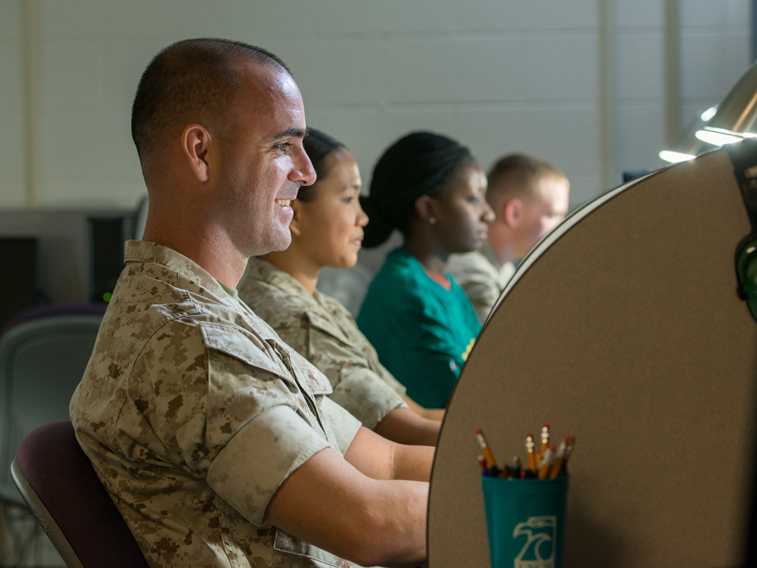 Man in military uniform sitting at a desk smiling