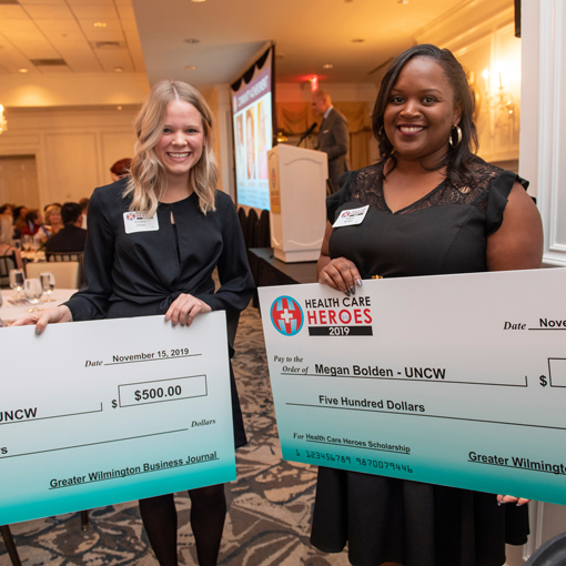 Two people holding giant checks at an event