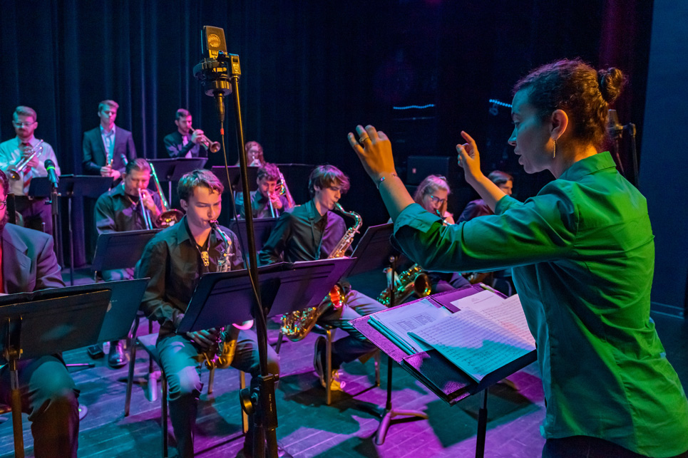 Conductor stands before a band as they perform a concert.