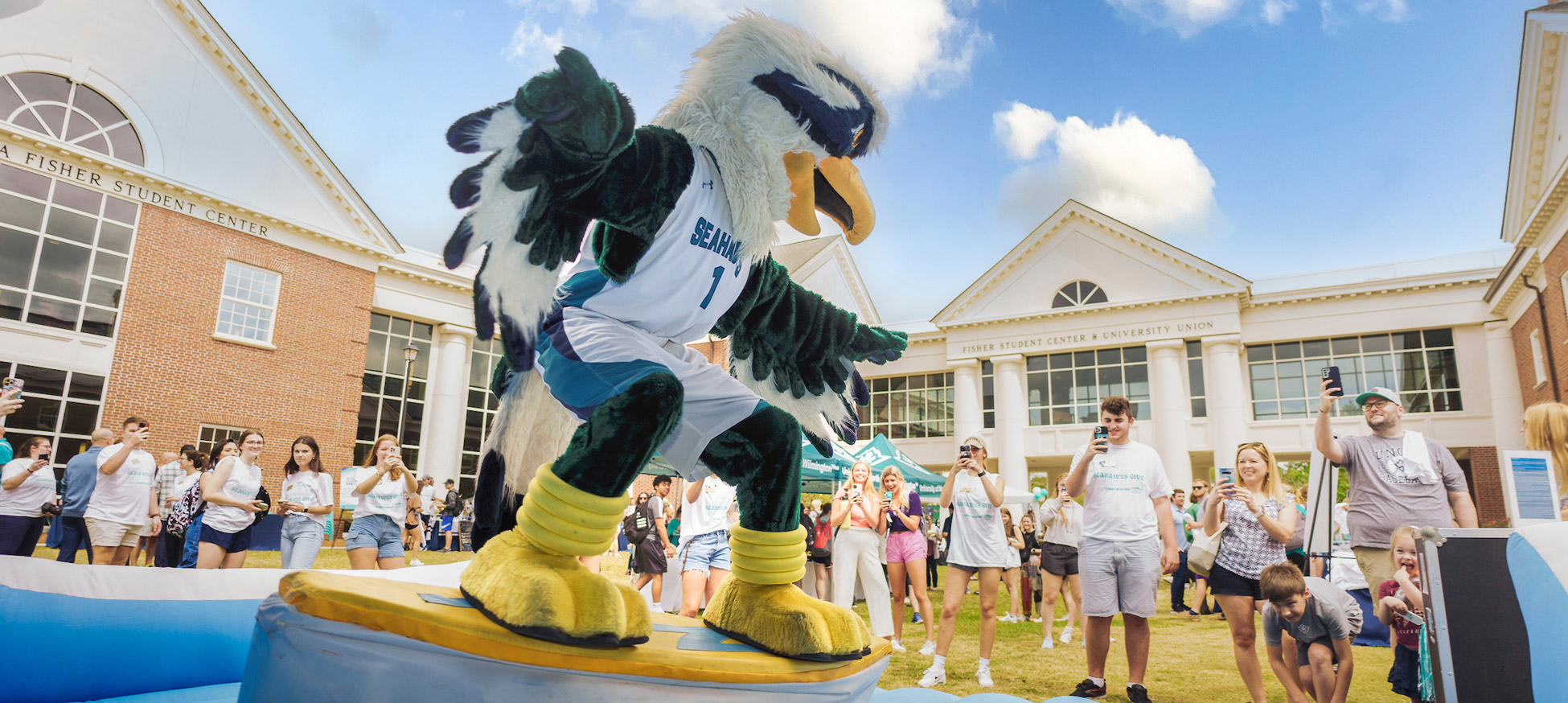 Sammy C. Hawk rides a surf simulator at a campus event