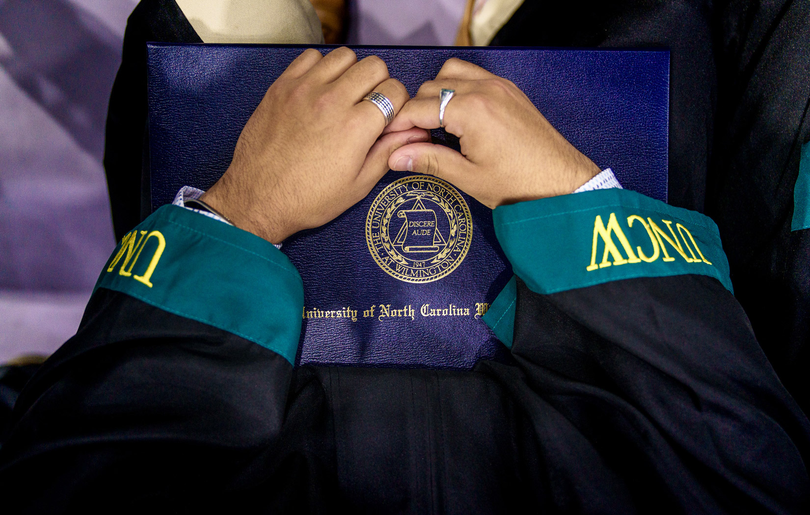 A person holding a UNCW diploma