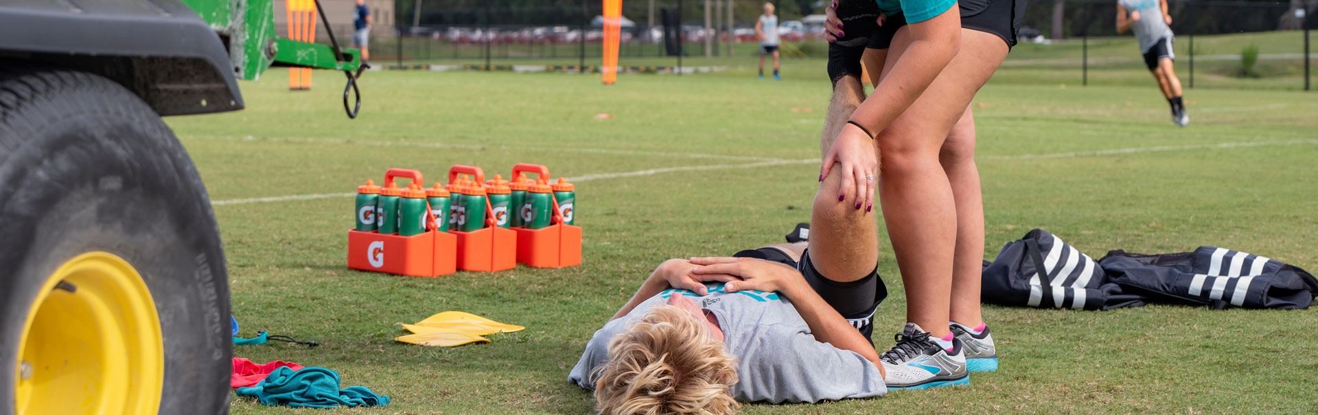 An athletic training student works on the leg of another student lying on the ground during a simulation
