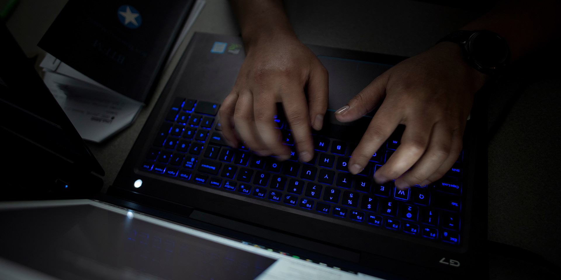Photo of a dark, lit up keyboard as someone types