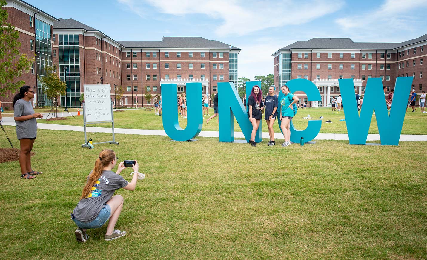 students pose in front of the UNCW letters on campus