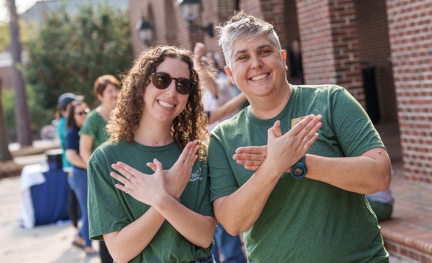 Two women giving the uncw seahawk hand signal