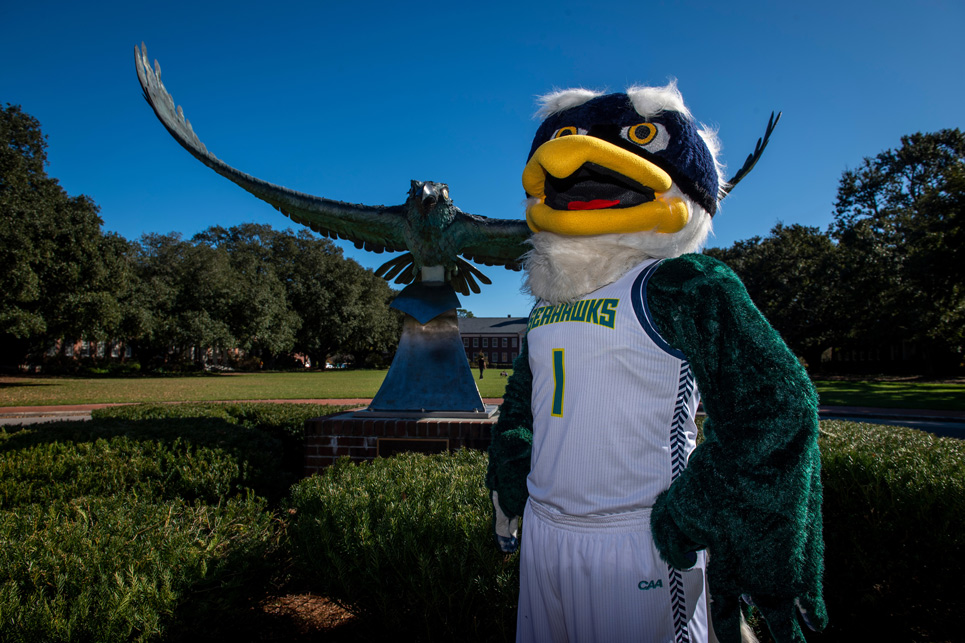 Sammy Seahawk standing in front of a Seahawk statue
