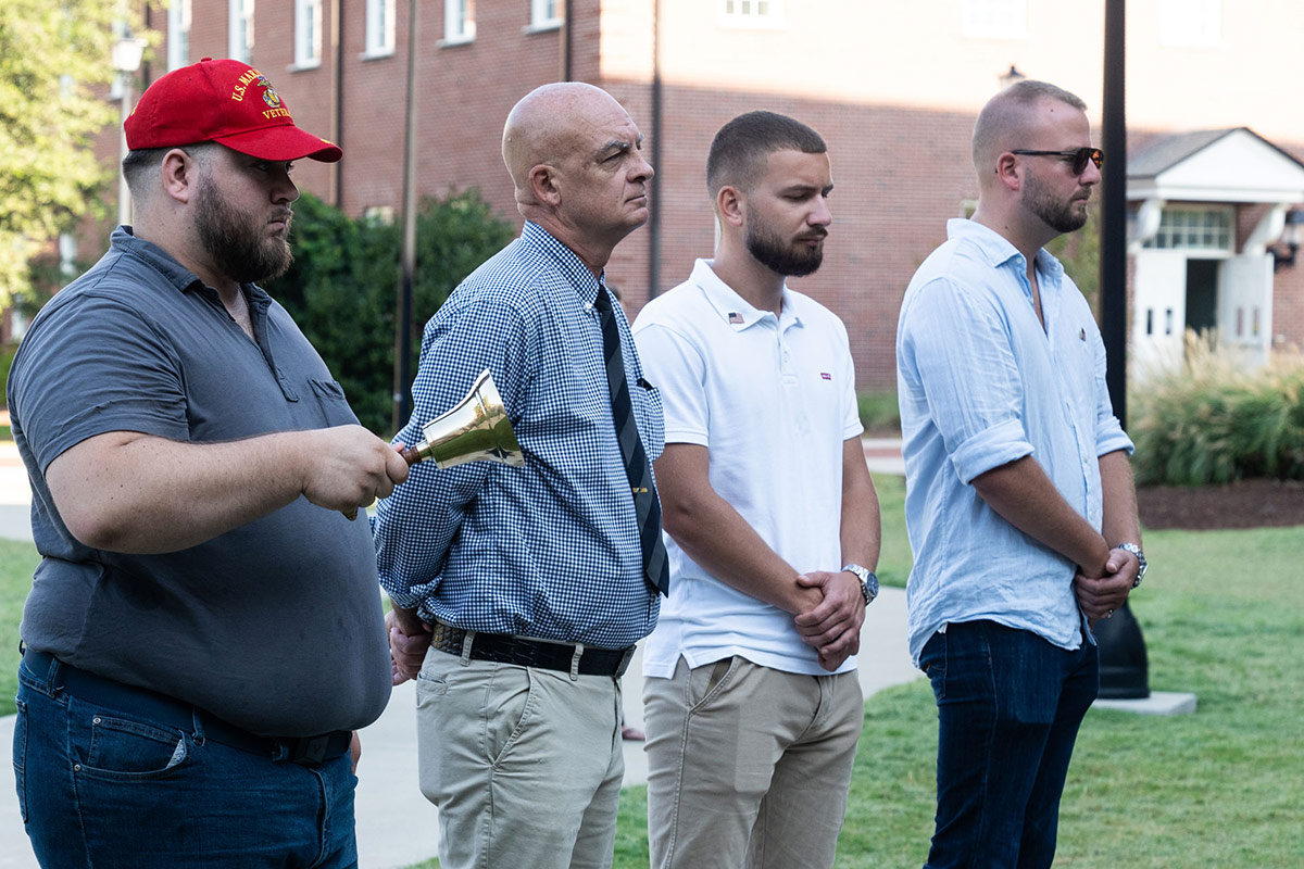 Bell ringer stands with others on Veterans Hall lawn