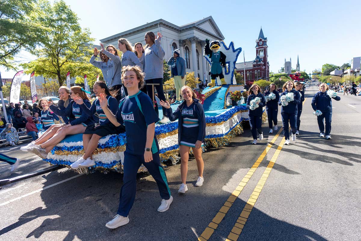 UNCW parade float with cheerleaders, dance team and women's basketball team members with Sammy C. Hawk