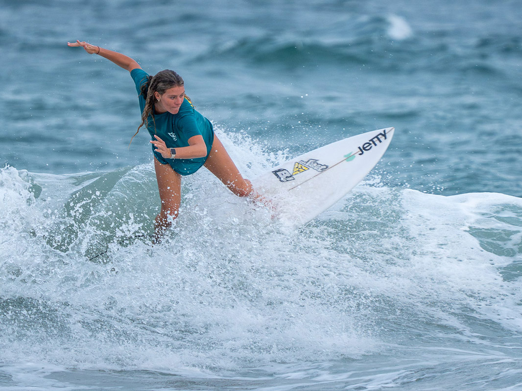 Mia Gallagher rides a wave on her surfboard