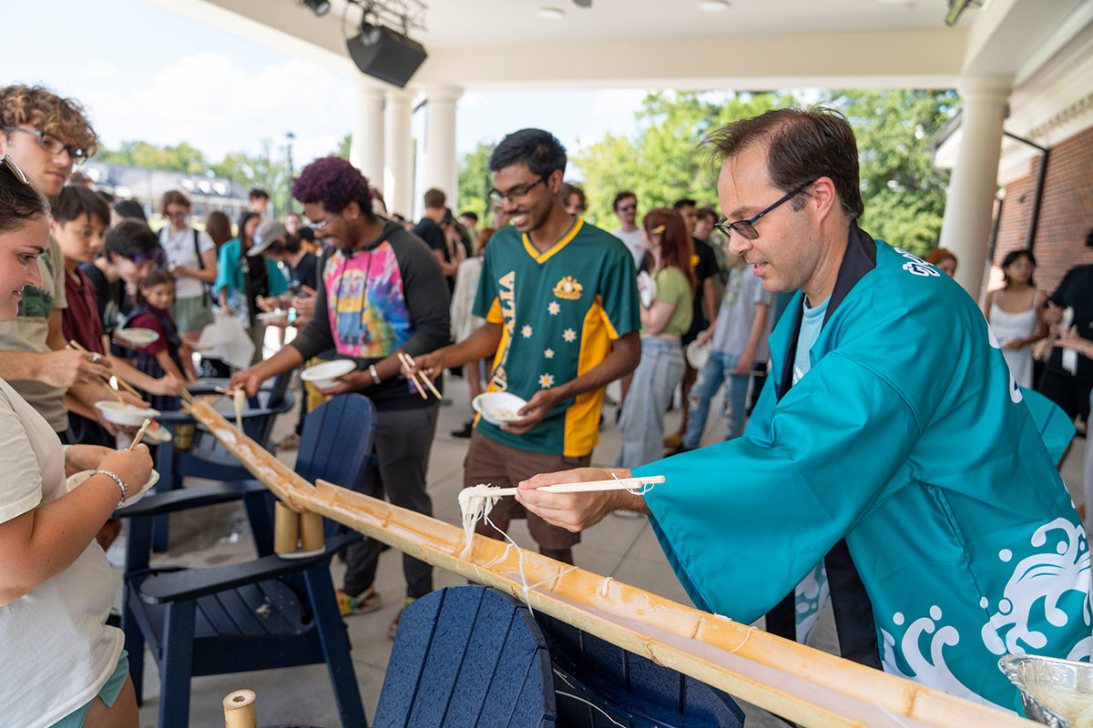 People use chopsticks to catch noodles from a bamboo chute at the Shoreline Sports Complex