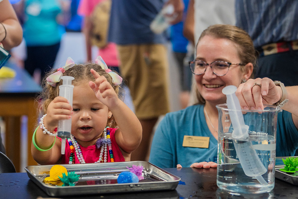 UNCW employee with a young girl at the CMS open house