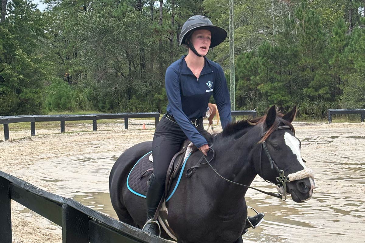 A student rides a horse during team practice