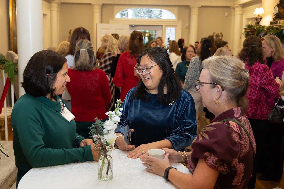 Dr. Ai Ning Loh stands at a table in Kenan House chatting with other women