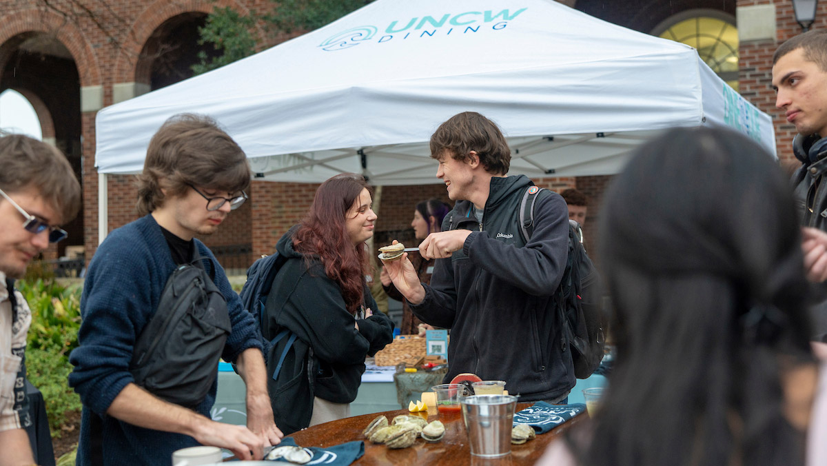 Students partake in the oyster roast in front of a UNCW Dining tent