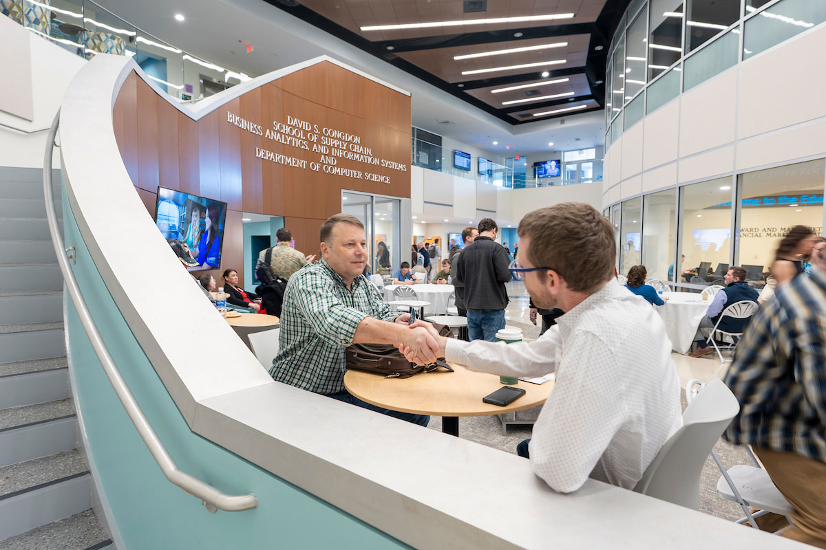 Two WITX attendees greet each other in Congdon Hall