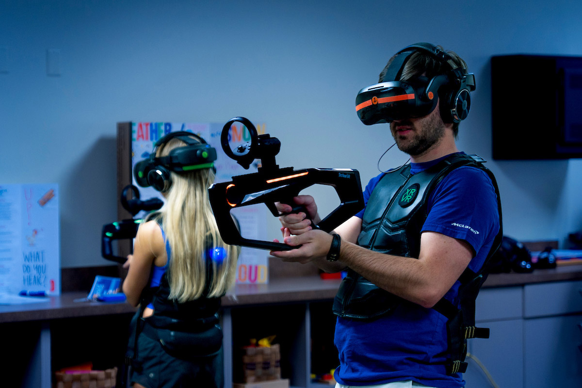 A gamer wears a headset and mask and holds a controller for a game