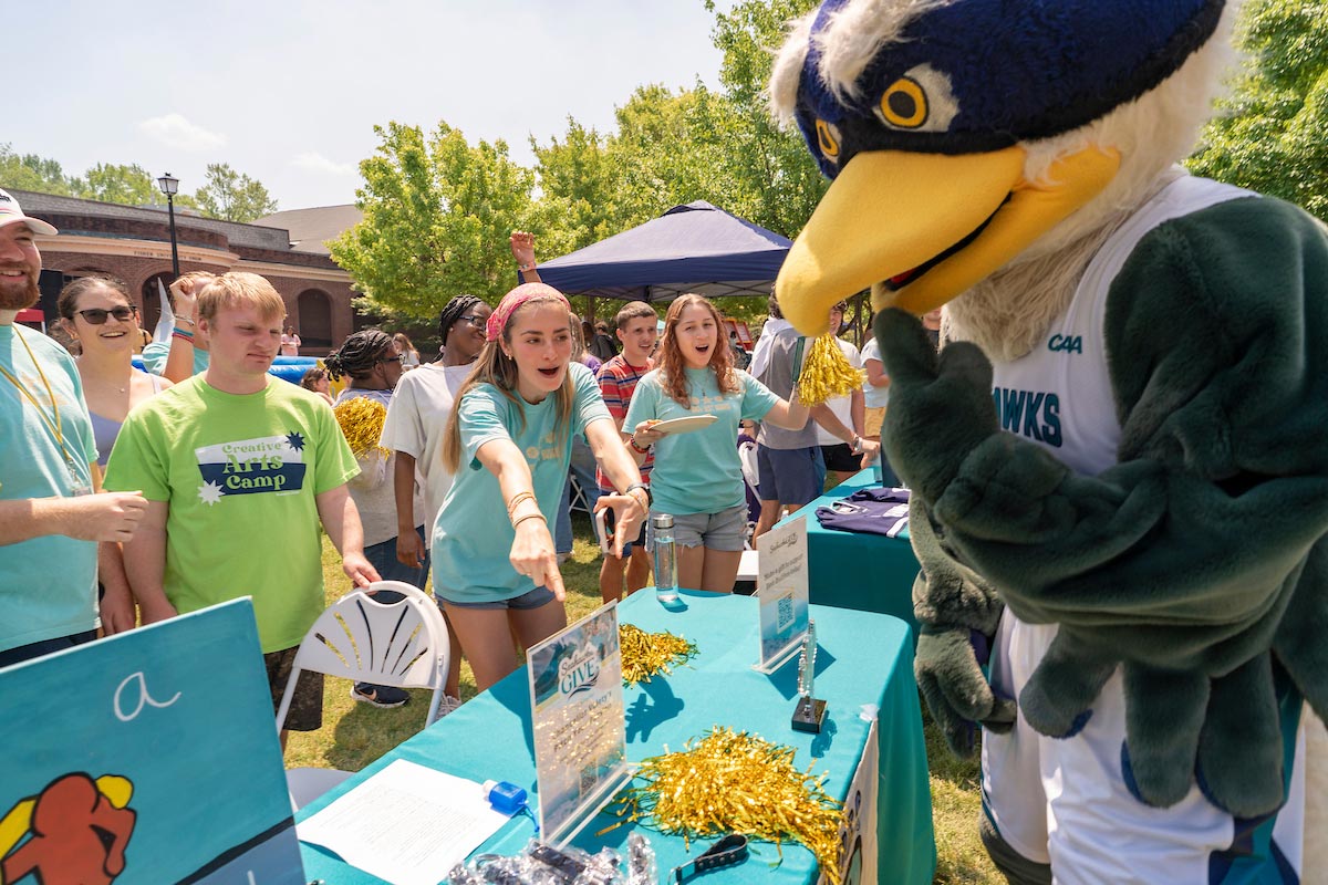 Sammy C Hawk and students at a table with Seahawks Give information
