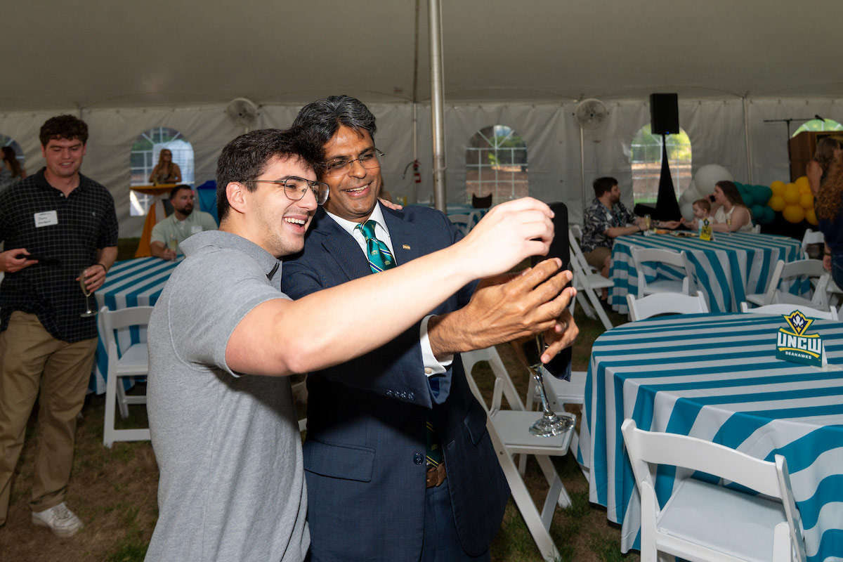 Chancellor Volety takes a photo with a soon-to-be-graduating Seahawk