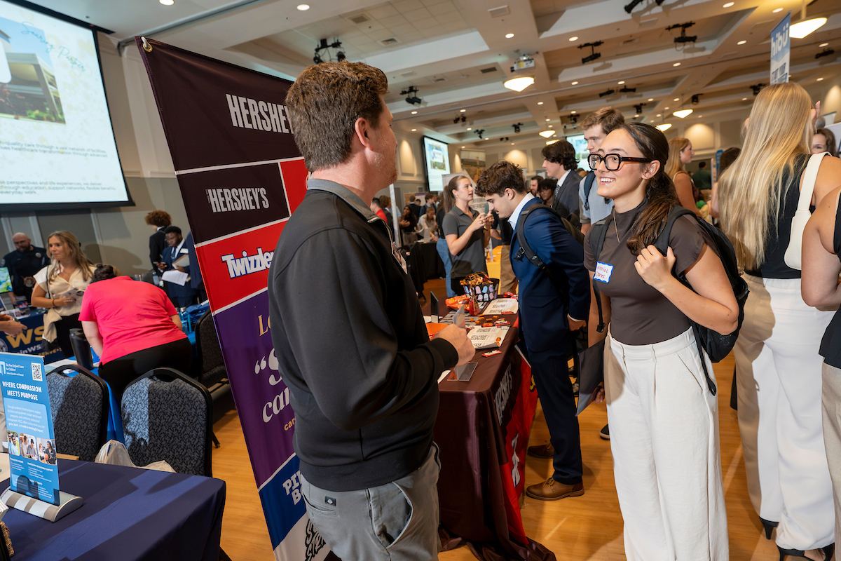 People congregate amid tables and banners at Career and Internship Fair