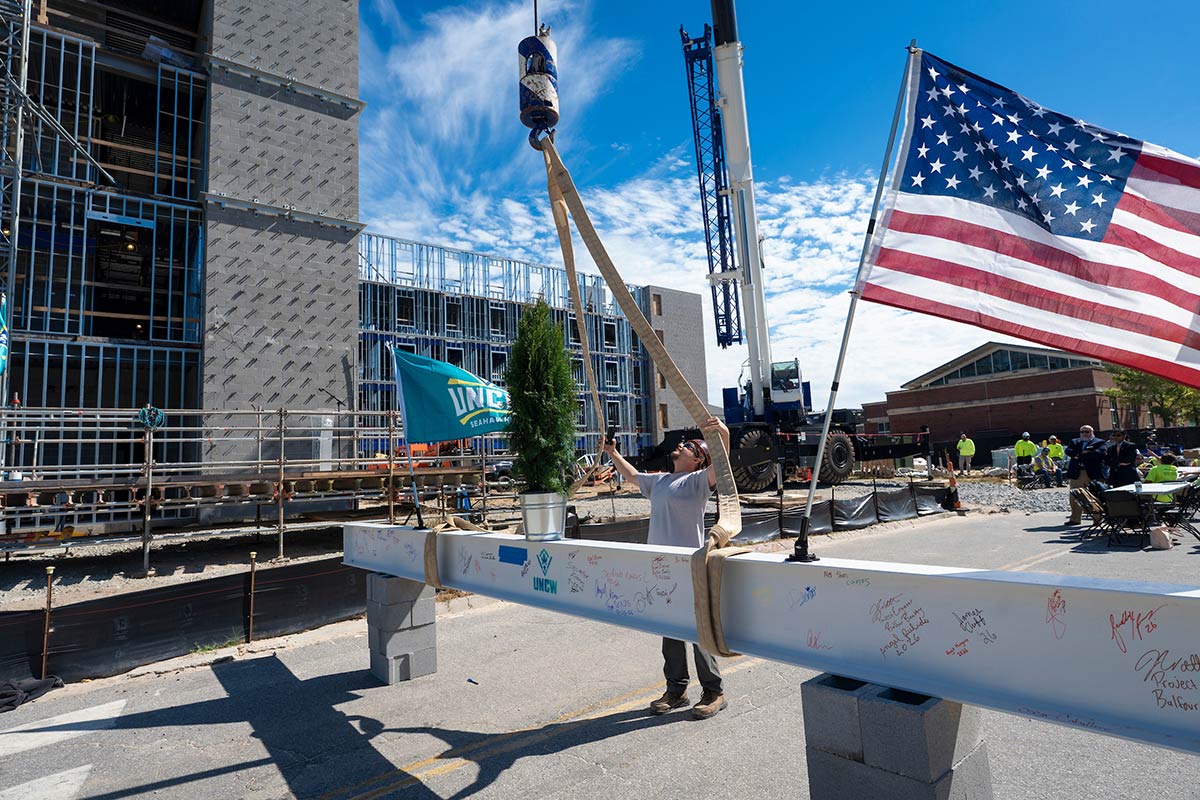 Worker connects the final structural beam to be lifted into place atop Hammerhead Hall