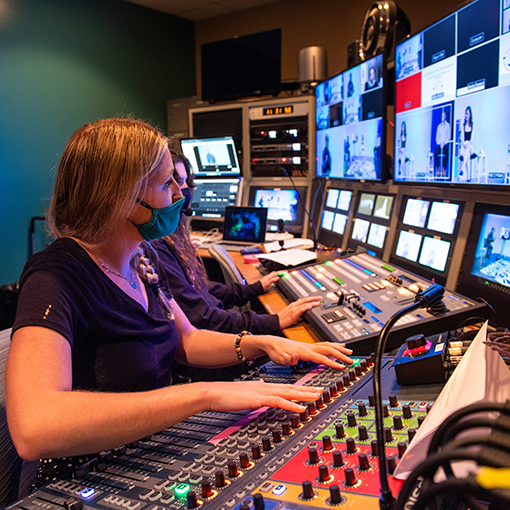 Student watches a broadcast and monitors the sound using a soundboard