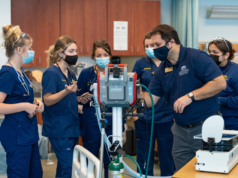 Students in scrubs looking at a device