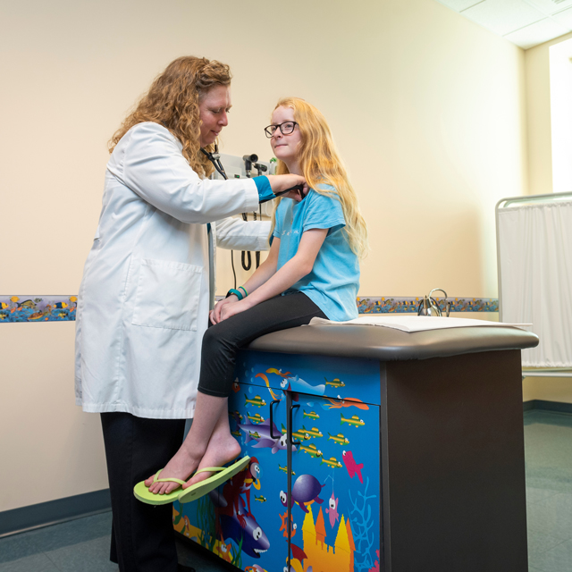 A nurse practitioner examines a child on an examination table
