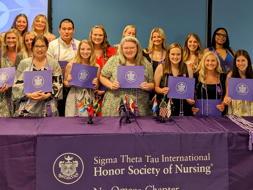 Inductees to Nu Omega pose for a photo holding their certificates.
