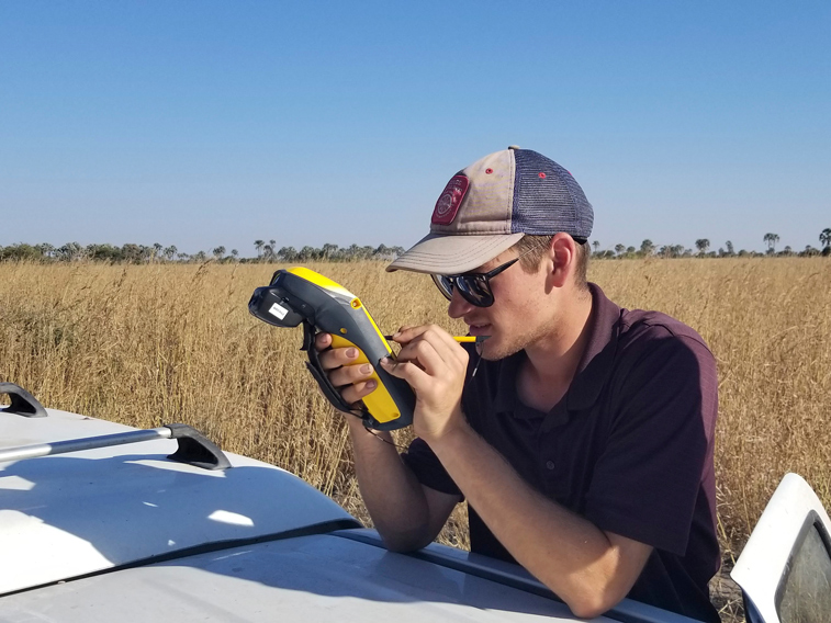 Student holds yellow gadget out in a field