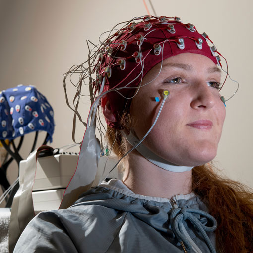 Woman sitting in a chair with a brain scanner on their head.