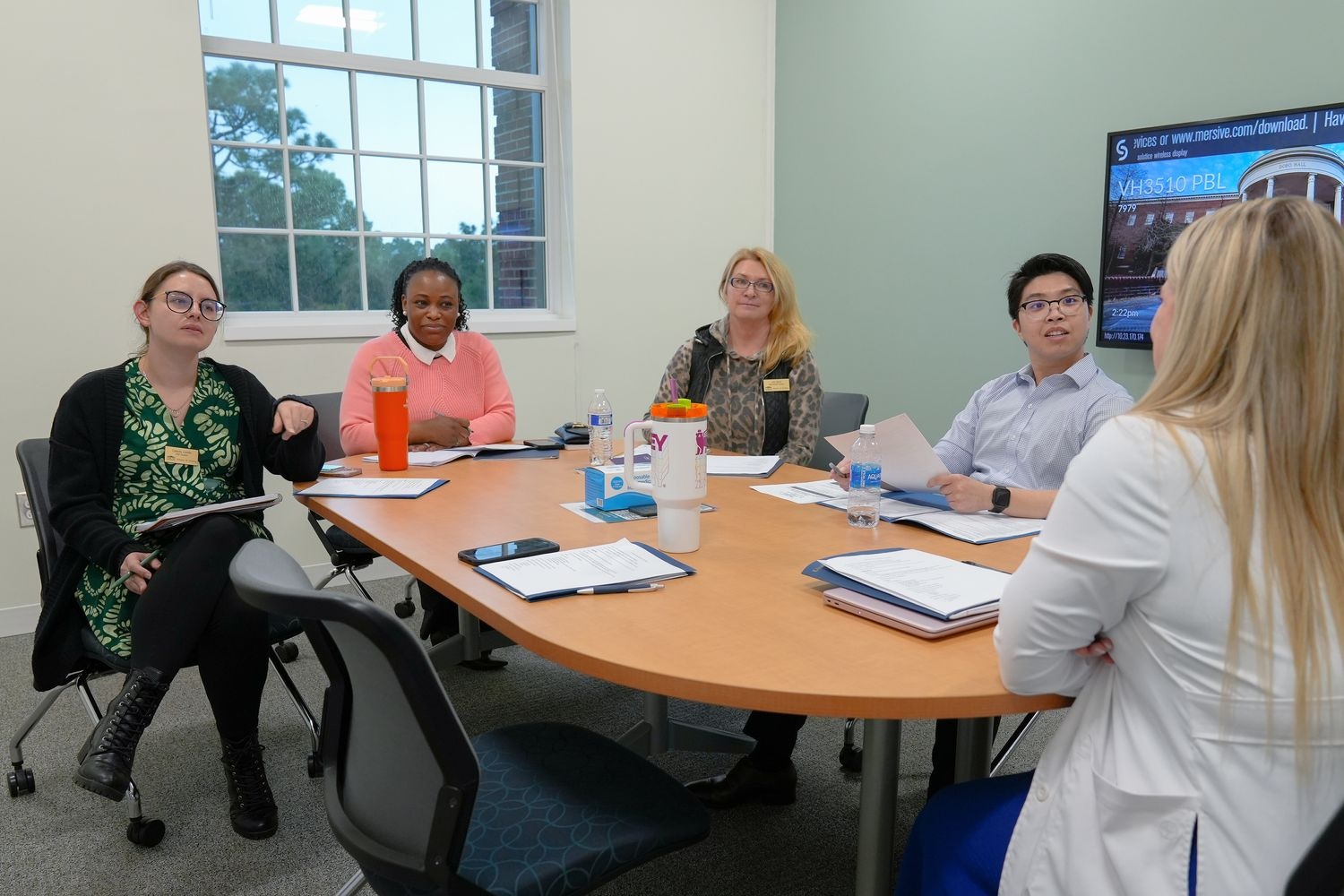 A group of five Psychiatric Mental Health DNP students share their notes and ideas at a round table discussion.