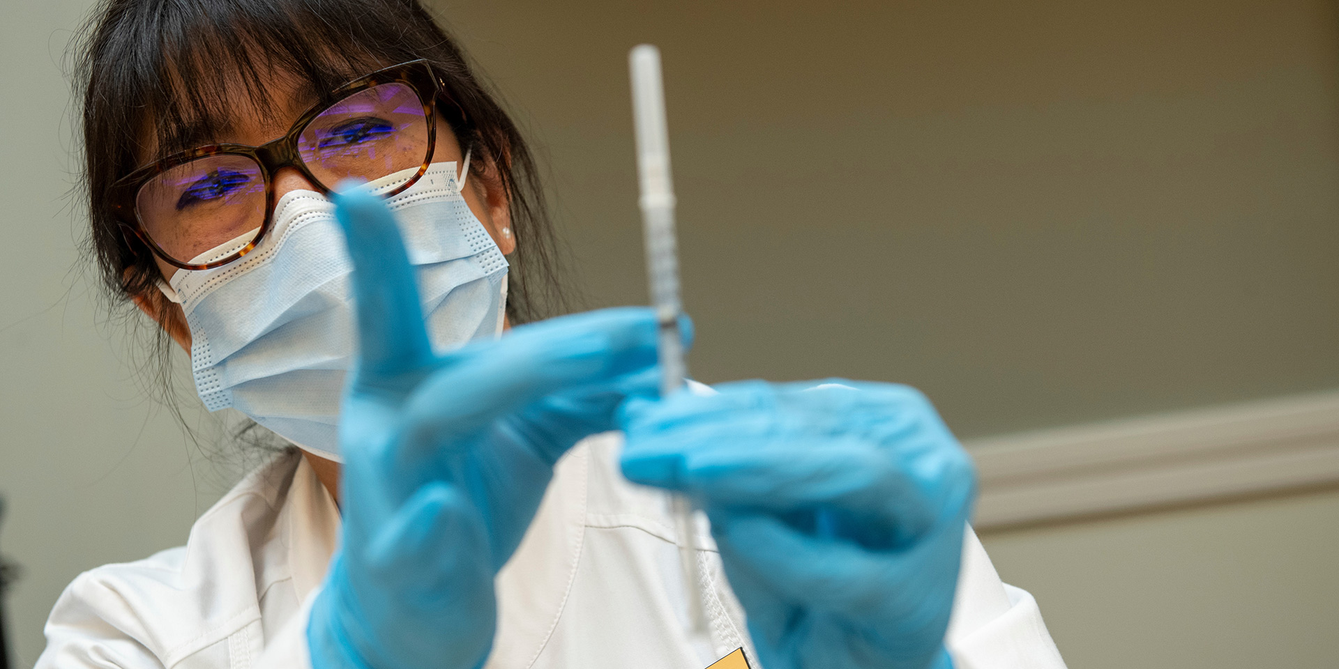 A nurse readies a syringe with a vaccine.