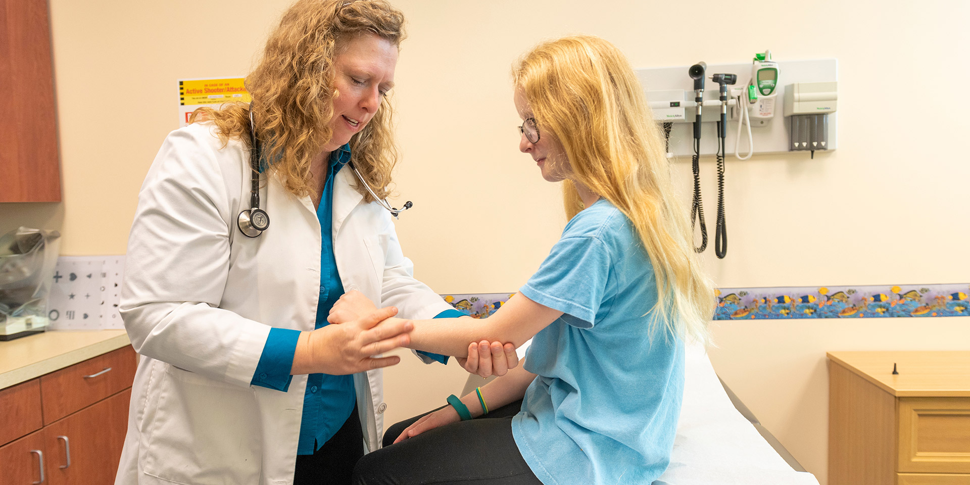 A nurse examines the arm of a child patient.