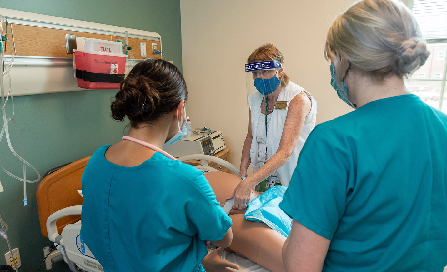 Nursing students practice with a labor and deliver mannequin.