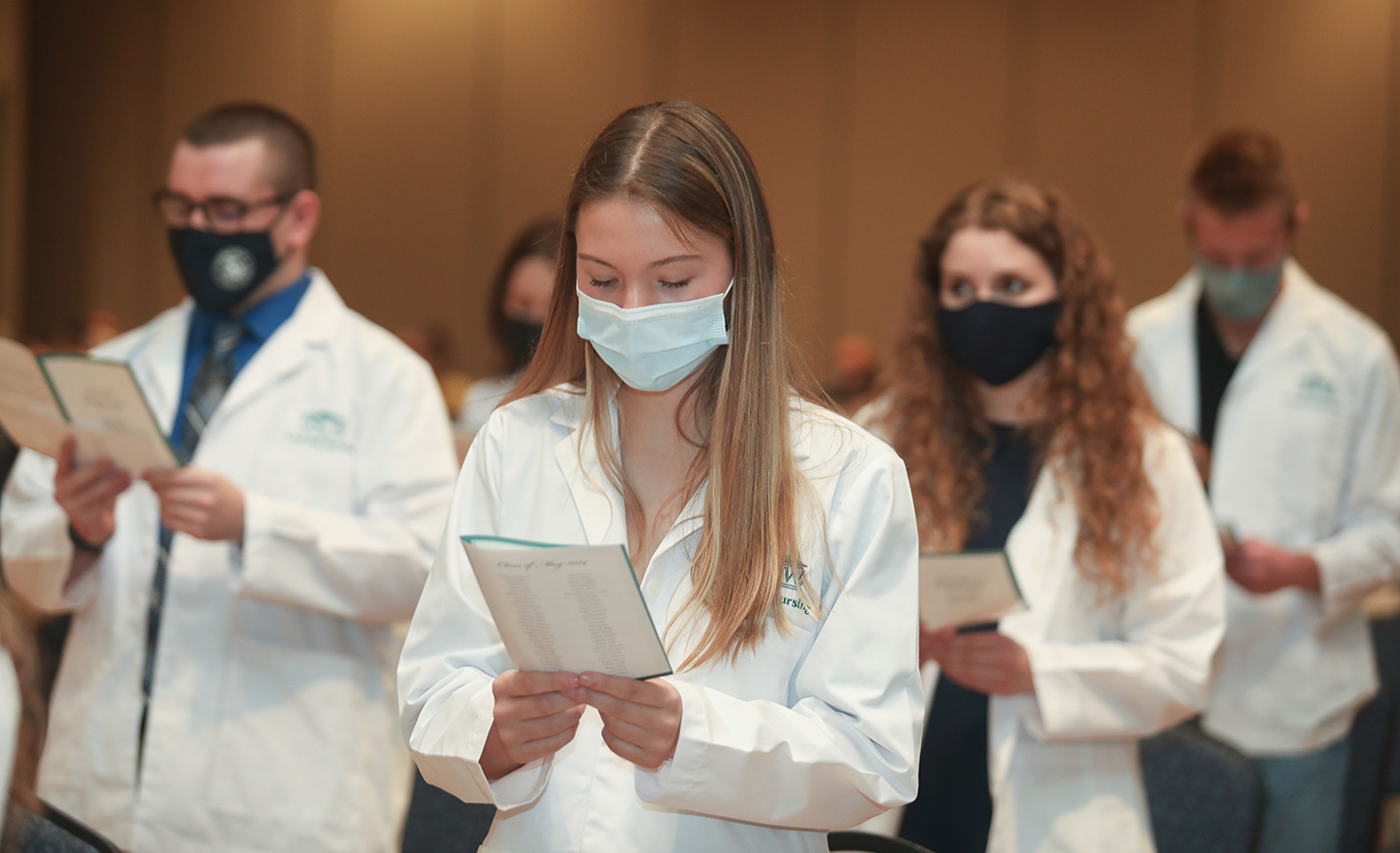 Nursing students stand in white coats for their white coat ceremony.