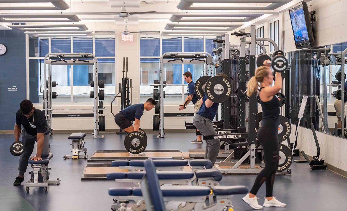 Several students lift weights in the student recreation center gym.
