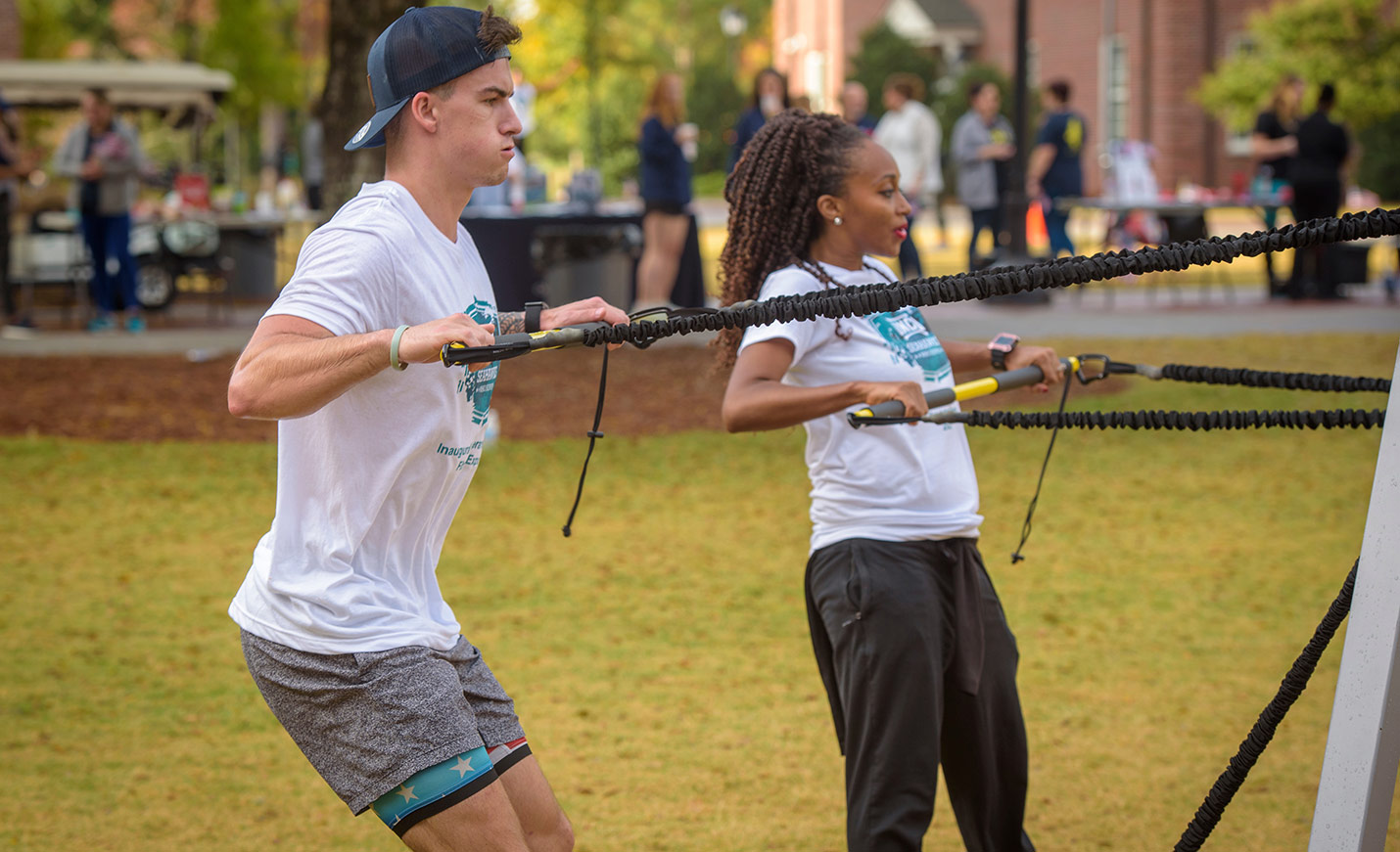 Two students do arm exercises outside at the annual veterans day expo fitness event.