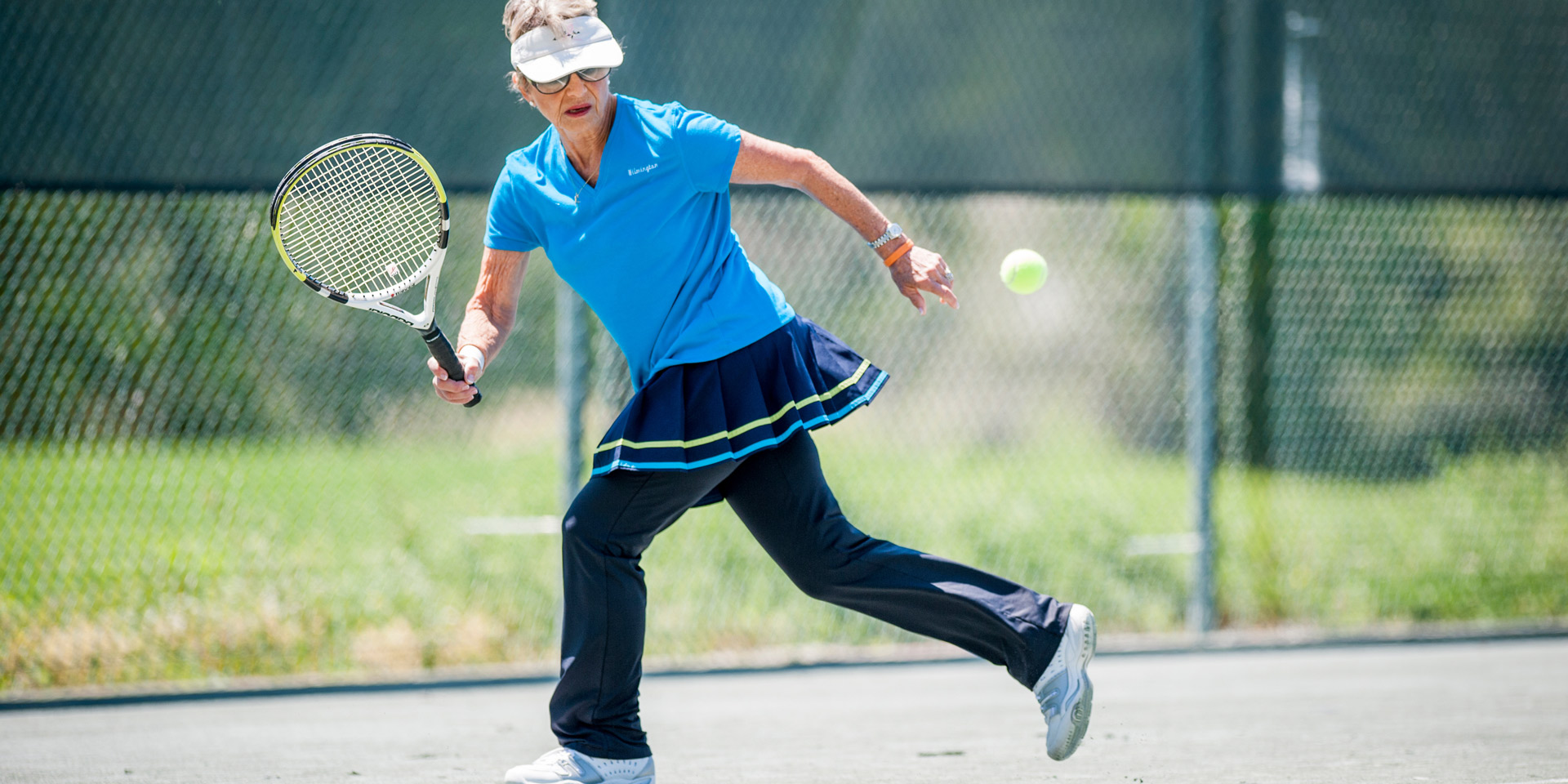 An older person runs for a tennis ball while playing tennis