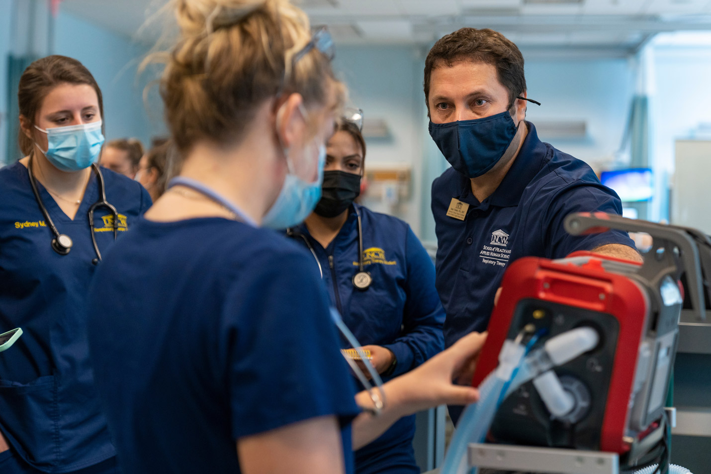 A respiratory therapy professor observes students while they practice with equipment.