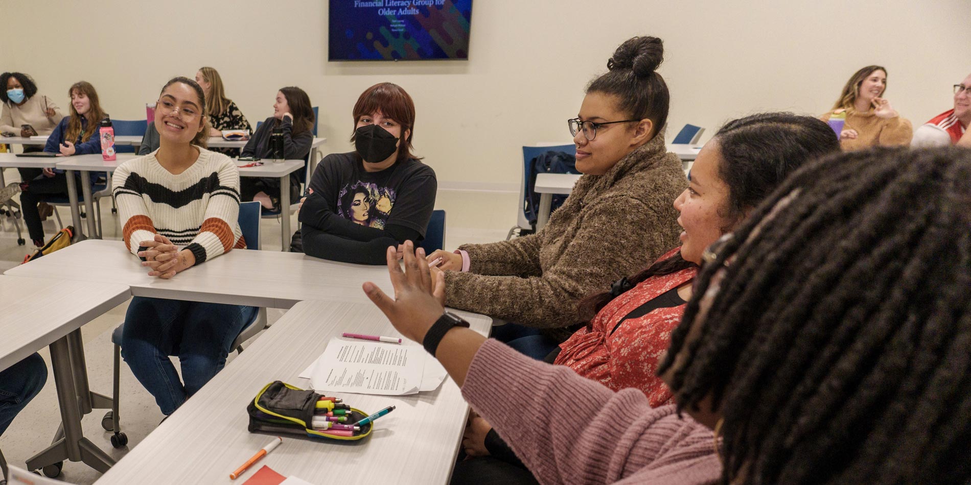 a group of social work students sit at tables and take part in a discussion.