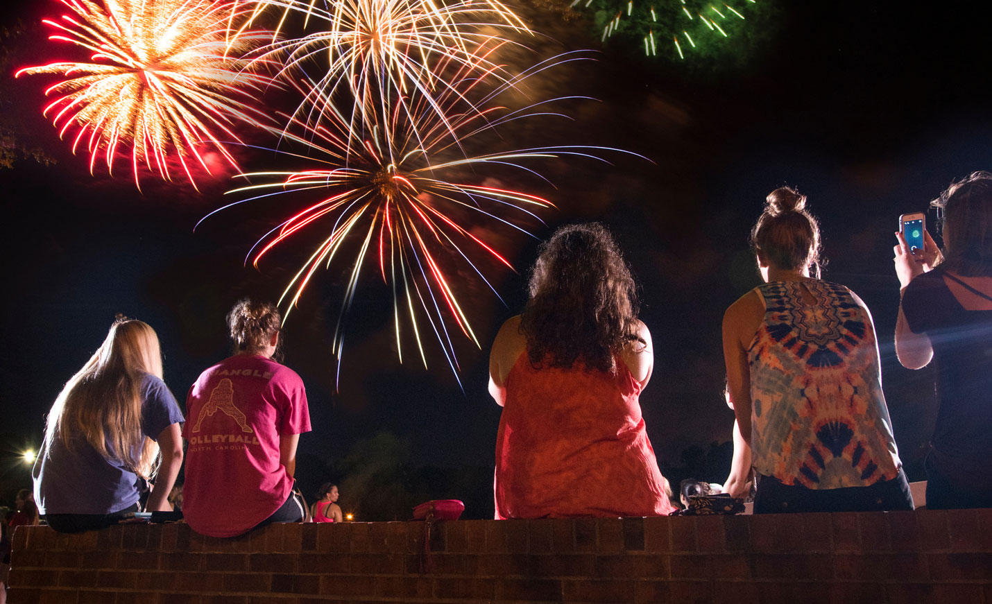 Five students sit while watching fireworks.