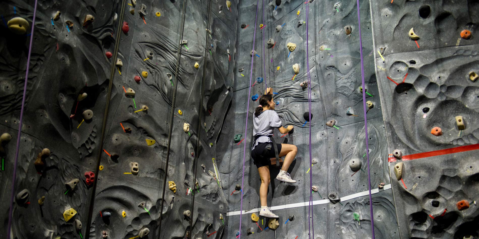A student climbs the rock climbing wall at the student recreation center on campus.