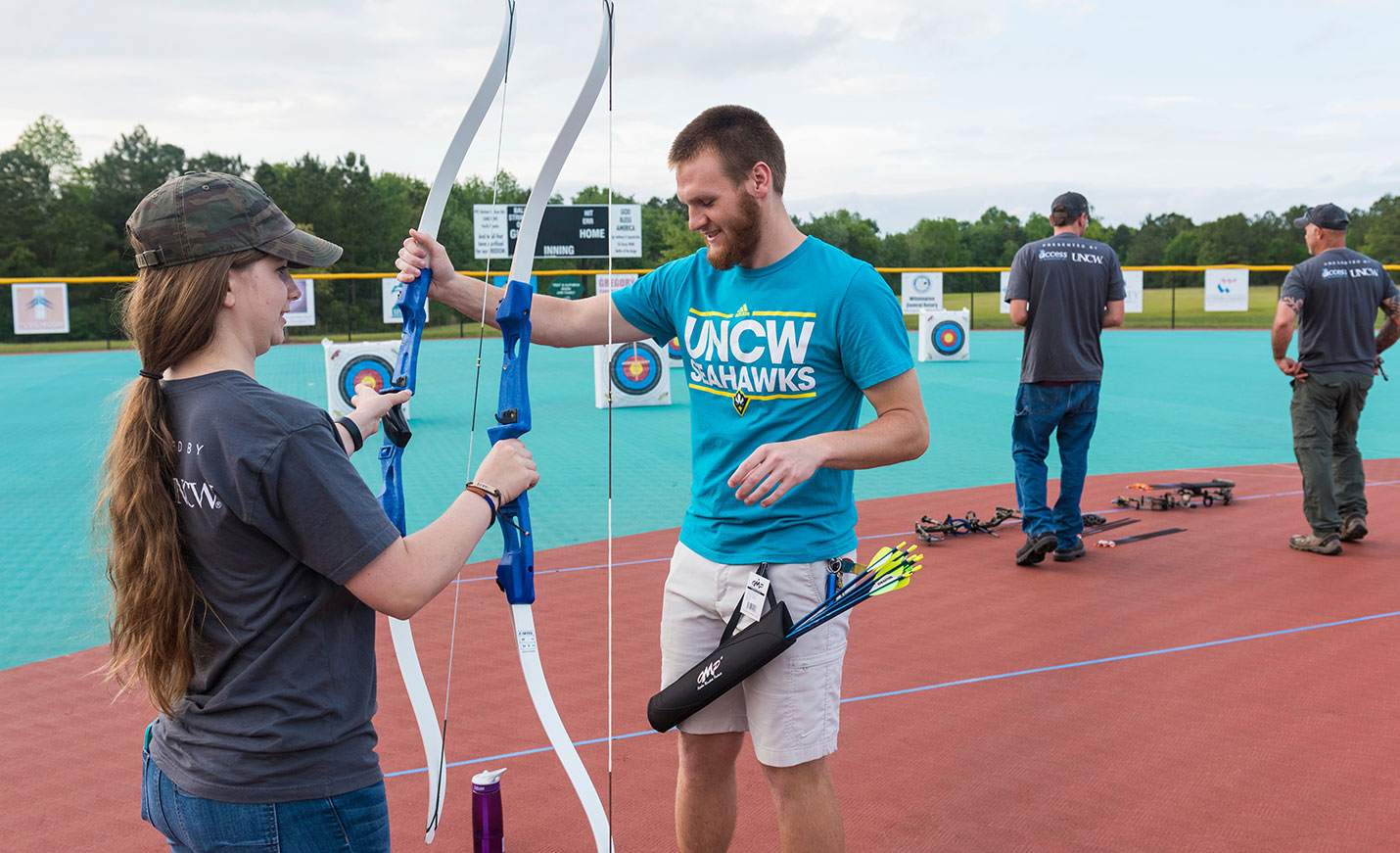 Students prepare two bows for an archery activity.