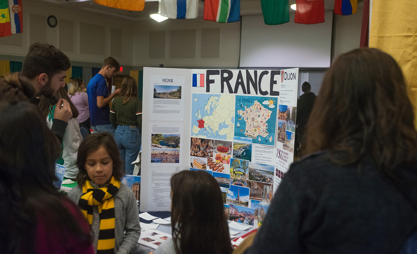 A poster about France stands on a table while people look at it